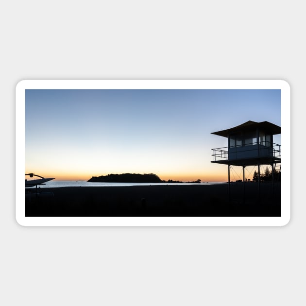 Silhouetted against golden glow of sunrise lifesafers lookout on Mount Maunganui beach New Zealand. Sticker by brians101